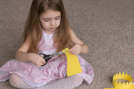 可爱的4岁小女孩用彩纸装饰打孔器和彩纸制作精美的应用装饰品背景图片