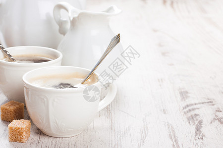 一杯咖啡与糖崽和牛奶壶白色老式木制背景上与复制空图片