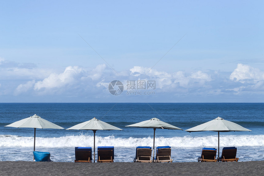 在海洋岸的白色雨伞与黑沙图片