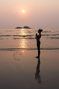 六项精进年轻瘦女人在日落时在海滩上背景