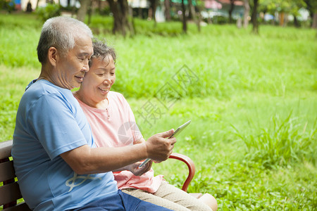 快乐的亚洲老年人夫妇与平板电脑图片