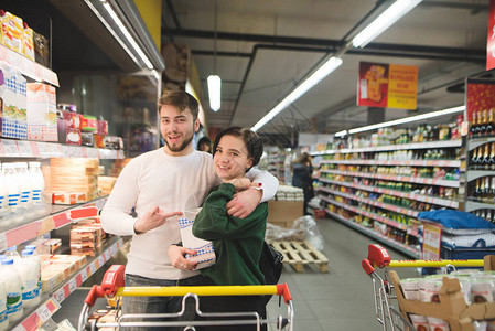 快乐的一对年轻夫妇在超市装扮着牛奶在超市图片