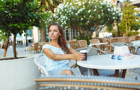 女青年在户外咖啡馆休息喝咖啡和看报纸在图片