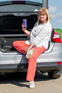 50岁的妇女在车里喝酒去野餐图片