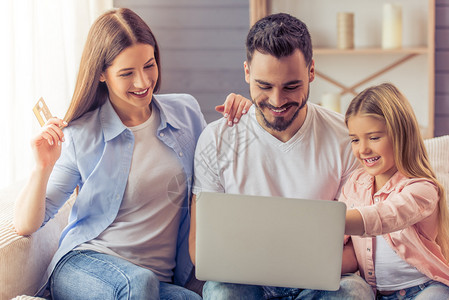 美丽的父母和他们的女儿正在用笔记本电脑在线购物图片