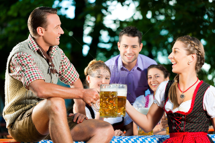 在啤酒花园里在德国巴伐利亚的TrachtDirndl和Lederhosen的朋图片