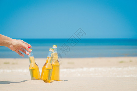 阳光明媚下沙子里的冰镇啤酒瓶图片