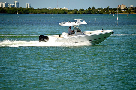 掌舵的父亲和坐在船头的儿子乘坐小型运动渔船在佛罗里达州沿海水道上背景图片