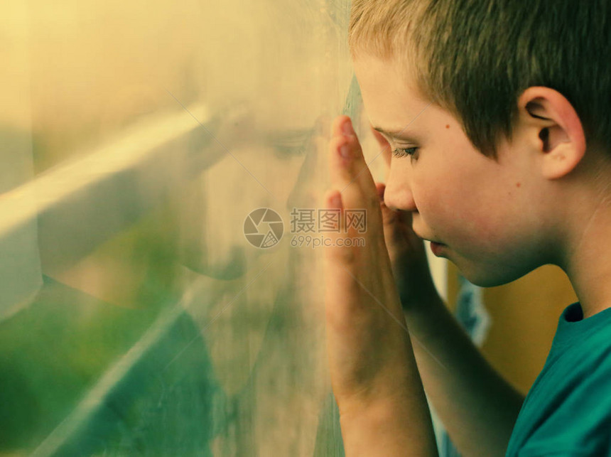 可爱的十岁自闭症男孩看着雨图片