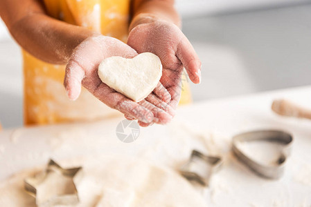 美籍非洲人儿童在厨房里手握着未烤熟饼干的心图片