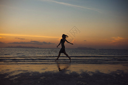 日落时在海滩上奔跑的女人剪影图片