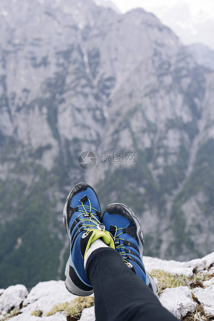 悬崖边上的女徒步旅行者鞋高地在下面的山上图片