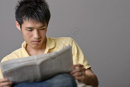 亚洲青年男子阅读报纸超过工图片