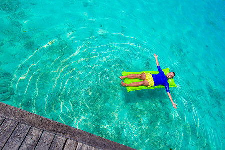 年轻人在海中的充气床垫上放松背景图片
