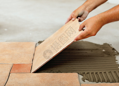 安装陶瓷地板砖瓦将瓷砖放在粘合材料图片