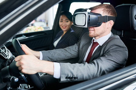 穿着古典西装的胡子男使用VR头盔学习驾驶汽车图片