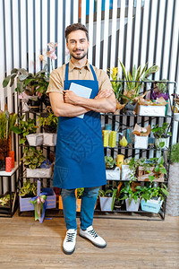 英俊的年轻花匠在花店工作时图片