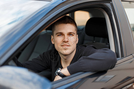 一辆黑汽车的英俊的年轻男司机背景图片