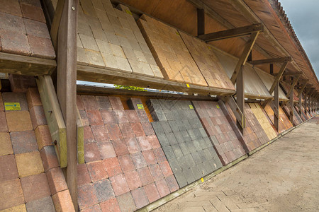 装饰铺面石和路砖在由露天木架室外储存供出售的展示货盘上组织的一个石图片