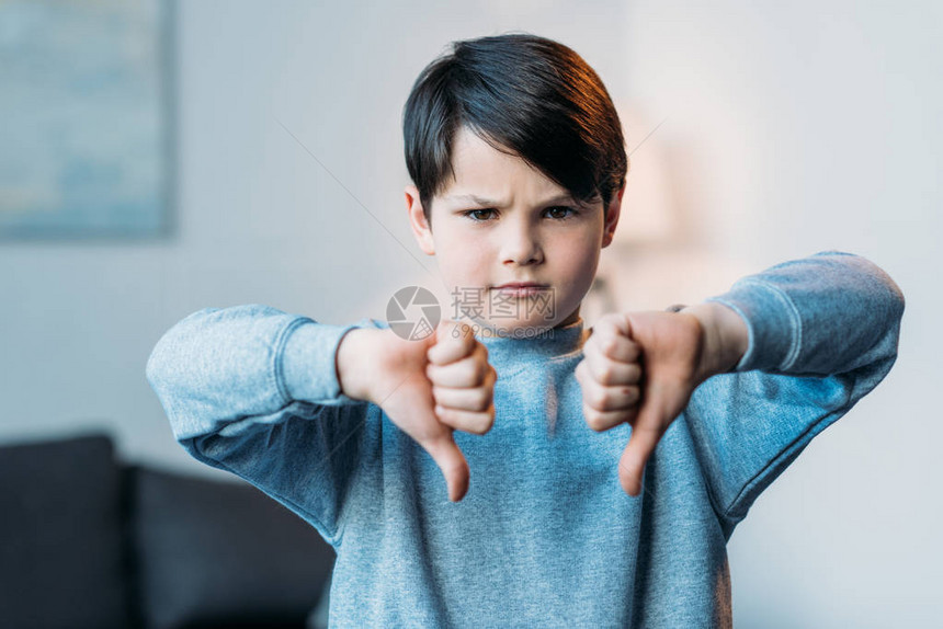 愤怒男孩的肖像显示低下拇指看着图片