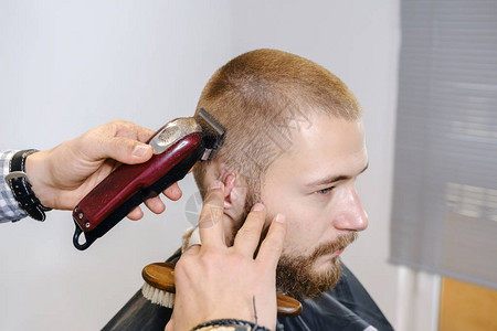 理发师用红色电动修剪器给客户剃光头背景图片