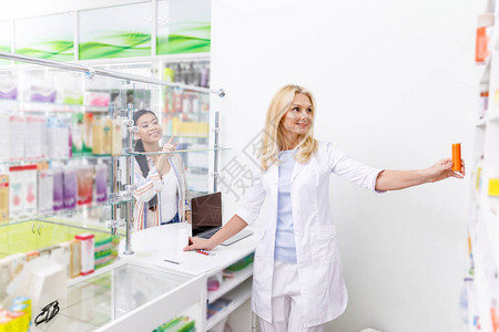 微笑着的女药剂师在顾客用手指对时从图片