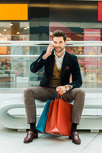 英俊帅气的时尚男子坐在购物中心装袋时图片