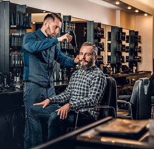 时髦的男理发师在酒馆里用吹发机背景图片