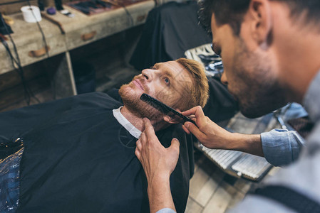 男理发师在理发店梳理顾客的胡须图片