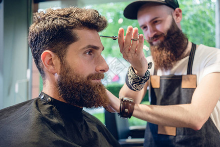 专职的男发型师使用剪刀和塑料梳子背景图片