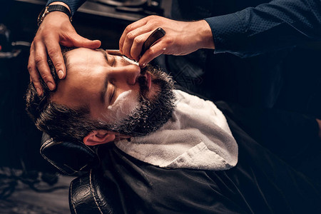 理发师用锋利的钢剃刀刮一个人图片