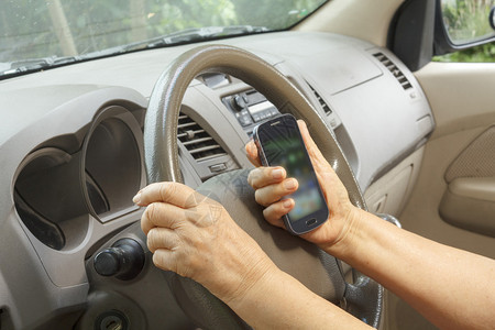 高级女驾驶汽车和手机接图片