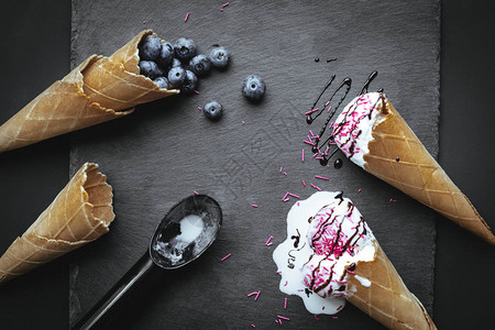 冰淇淋和蓝莓在石板上方的圆饼锥中融冰淇淋和蓝背景图片