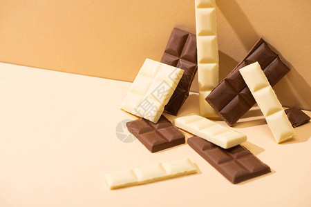 米色背景上甜美可口的黑巧克力牛奶巧克力和白巧克力图片
