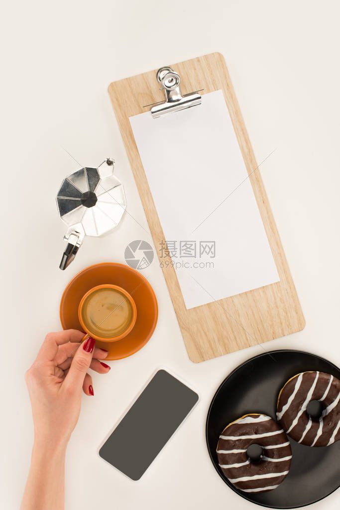 白色剪贴板上有咖啡杯和空白纸页的人类图片