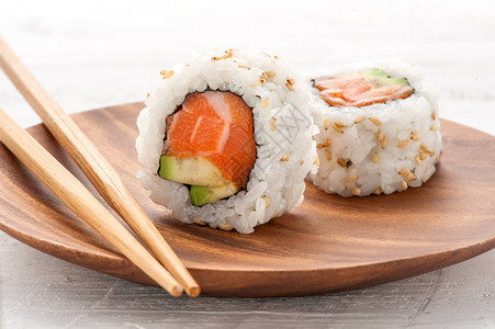 两条新鲜的鲑鱼和鳄梨寿司乌拉木板上配着一副木板一个站立直图片