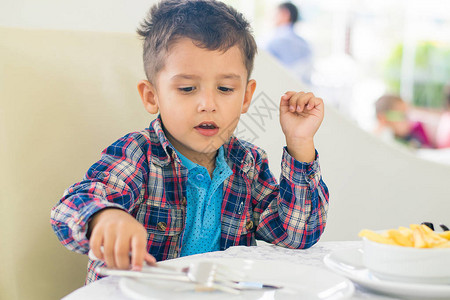 走姿礼仪4年的男孩在咖啡馆吃东西背景