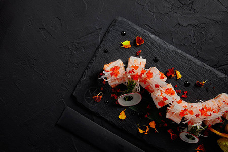 在石板上用虾鲑鱼和鳄梨制作的mamenori美味卷的顶部视图图片
