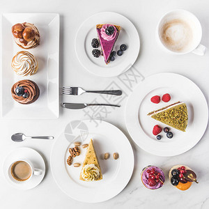 盘子上各种蛋糕咖啡杯和白纸杯蛋糕的排列图背景图片