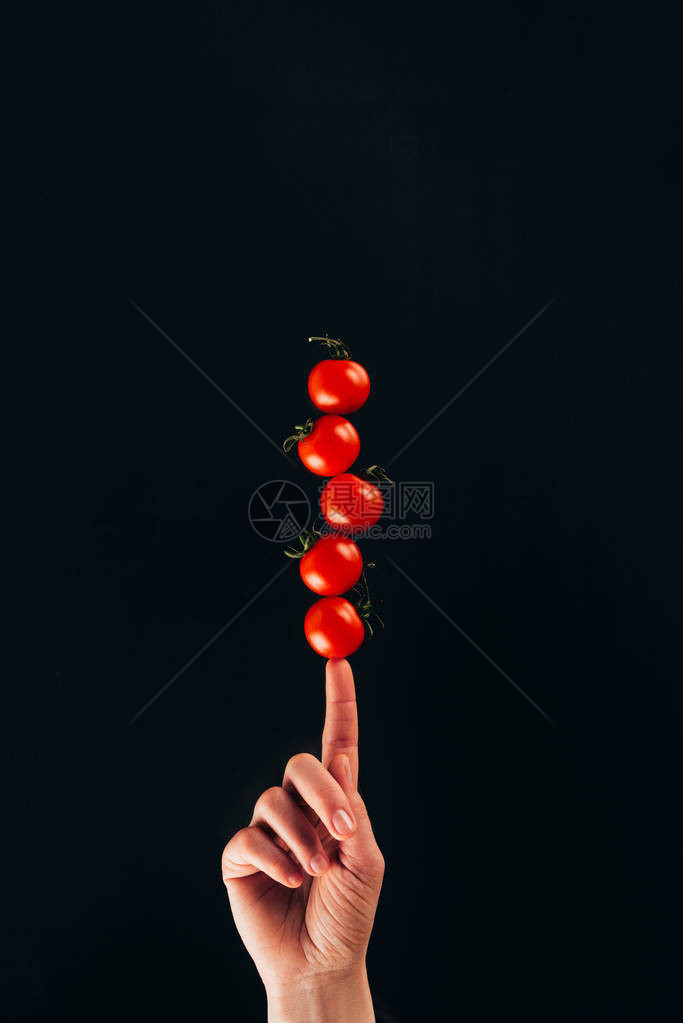 用黑色隔开的手指拿着樱桃番茄的女人的短片图片