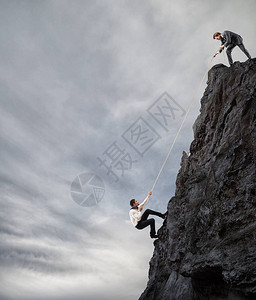 商人帮助另一个人攀登山峰图片