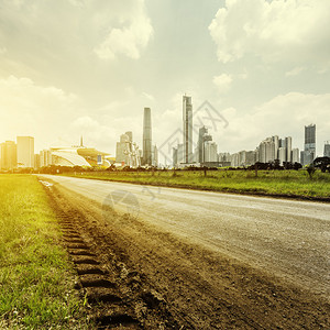 泥泞的小路和草地阳光下的摩天大楼图片