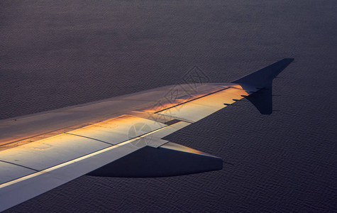 机翼飞机越海面日落光反射图片