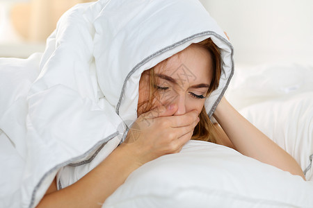 女感到病痛和头部被毯子遮住不健康图片