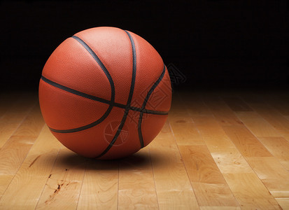 硬木健身房地板上的深色背景篮球背景图片