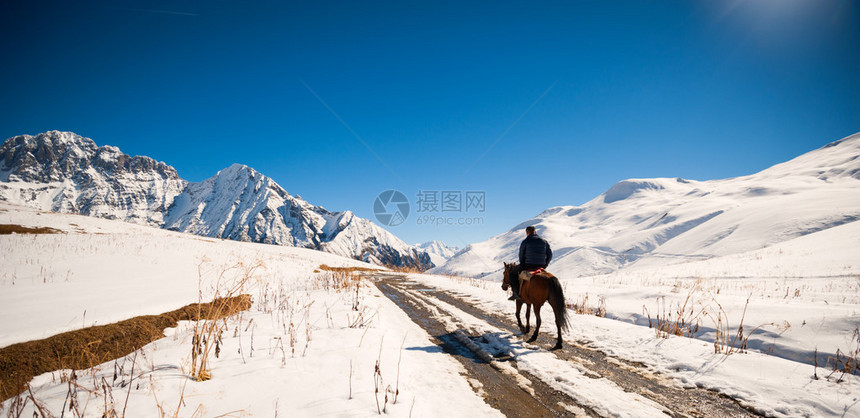 骑马的骑手在高加索地区白雪皑的山峰中图片