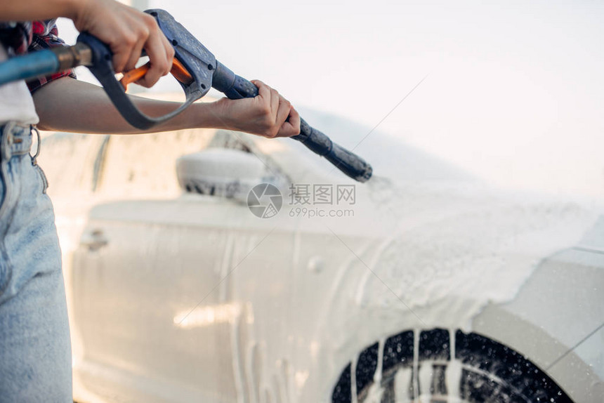 女洗掉汽车上的泡沫自助洗车的年轻女子夏日图片