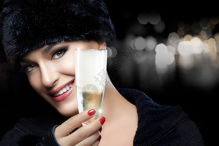 冬美人美丽年轻美女的特写盛情喜悦的毛皮帽和香槟敬酒高图片