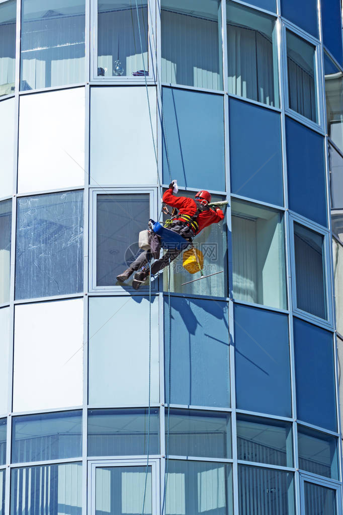 工人戴头盔从外面清洗高楼大的窗户图片