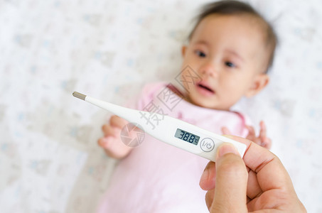 母亲用数字温度计测量生病婴儿的温度图片